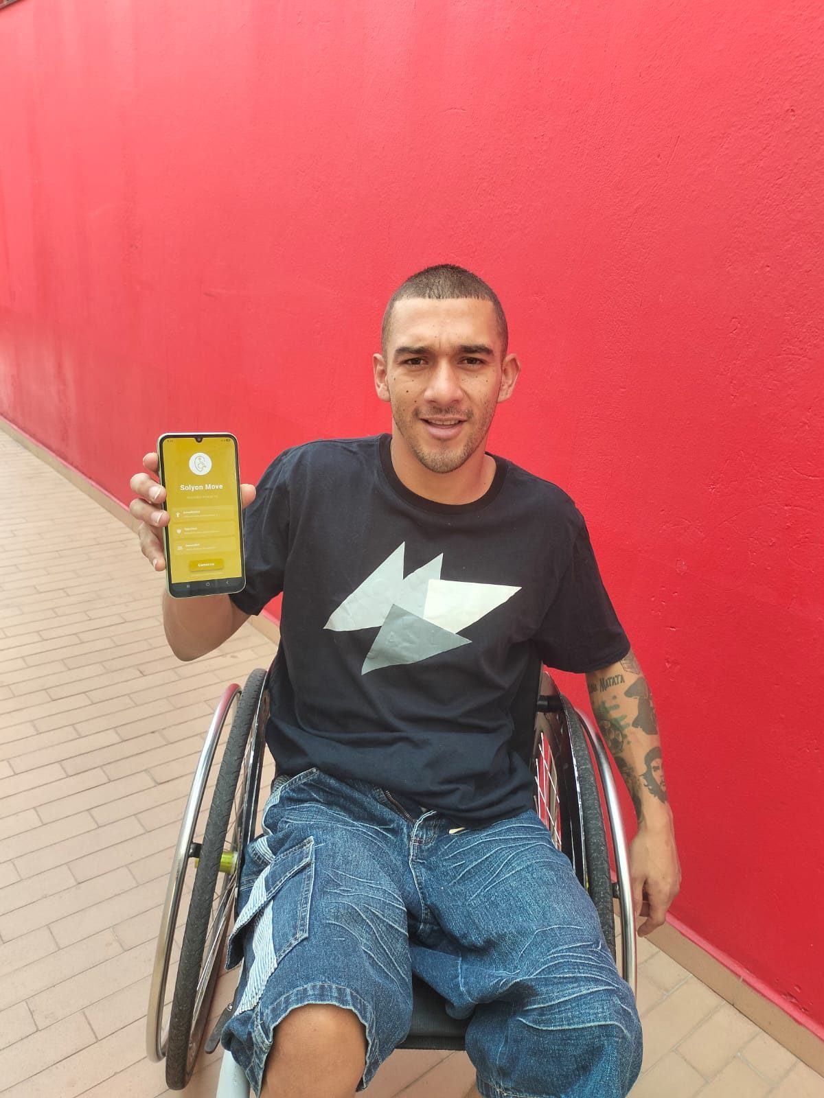 Usuario en silla de ruedas muestra la app SOLYON Move en su teléfono